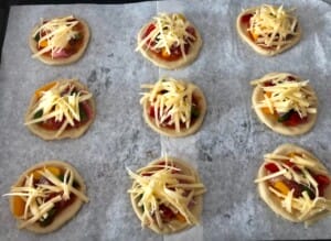 mini pizzerinki posypane serem przed pieczeniem