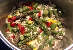 Przepis na risotto ze szparagami w trakcie gotowania z warzywami