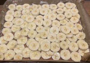 Banany skropione sokiem z cytryny Plasterki bananów ułożone na cieście przed zalaniem galaretką