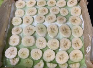 Zalewanie bananów galaretką Pierwsza warstwa zielonej galaretki utrwalająca banany w cieście shrek