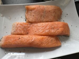 surowa ryba przyprawiona solą i pieprzem przed smażeniem