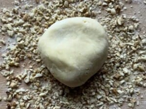 Ciasto rozwałkowane na kształt koła na warstwie posiekanych orzechów