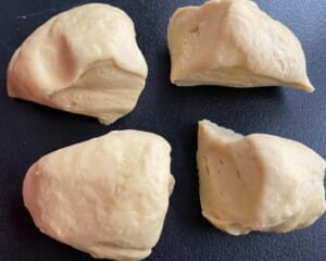 Gładkie ciasto podzielone na cztery równe kawałki na stolnicy